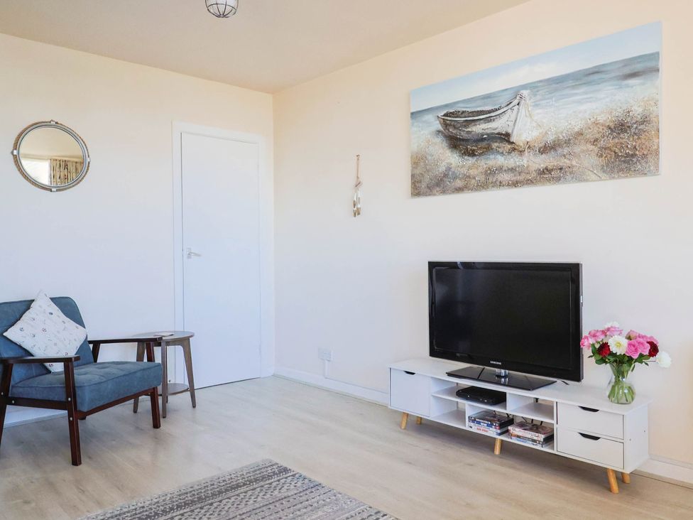 A living room with a television and an armchair at 16 Old Shipyard Centre in West Bay
