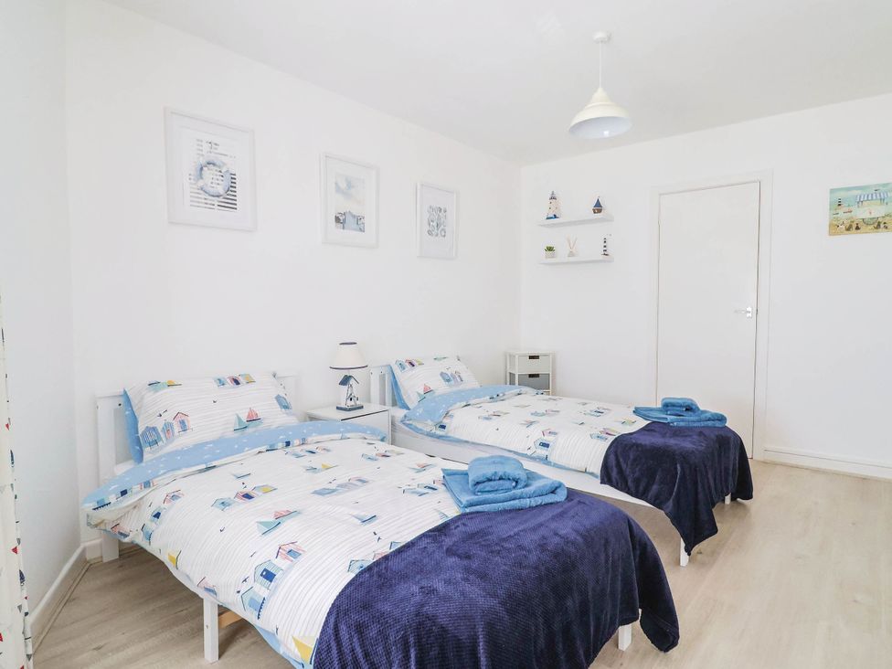 A bedroom with two beds and a lamp at 16 Old Shipyard Centre West Bay