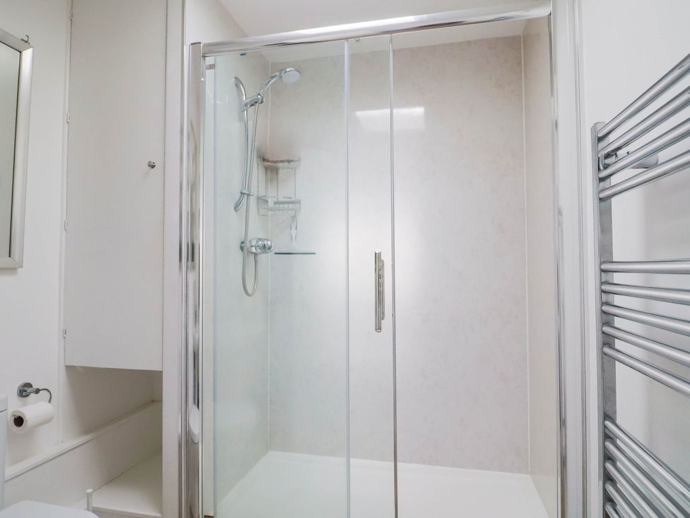 A bathroom with a shower and a mirror at 16 Old Shipyard Centre, West Bay