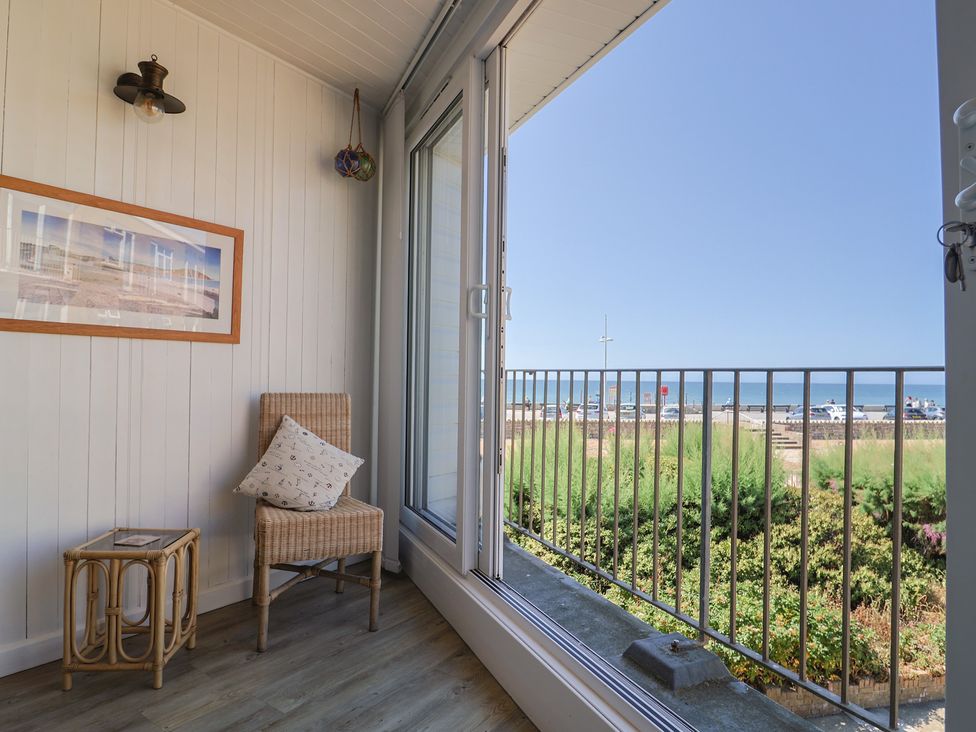 A balcony with a chair and side table at 16 Old Shipyard Centre in West Bay
