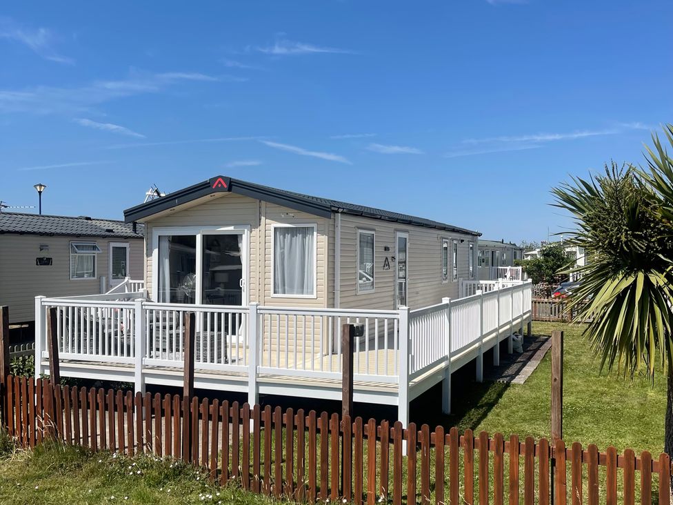 A mobile home with a deck and a fence at Unity Beach in Burnham-on-Sea