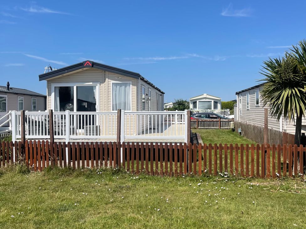 A static caravan with a deck and fenced area at Unity Beach in Burnham-on-Sea