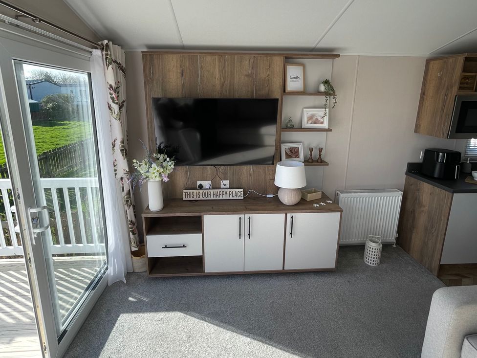 A living room with a television and shelves at Unity Beach Burnham-on-Sea