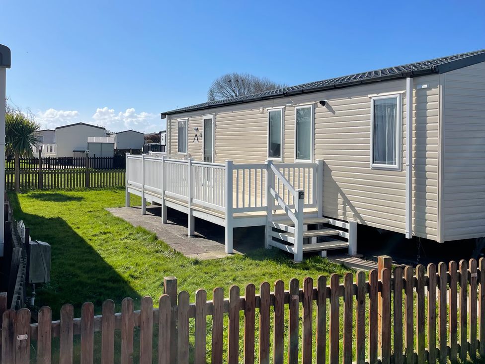 A mobile home with a deck and fenced outdoor area at Unity Beach in Burnham-on-Sea