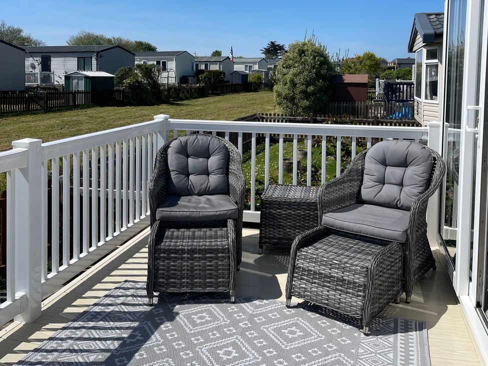 A deck with chairs and a table at Unity Beach in Burnham-on-Sea