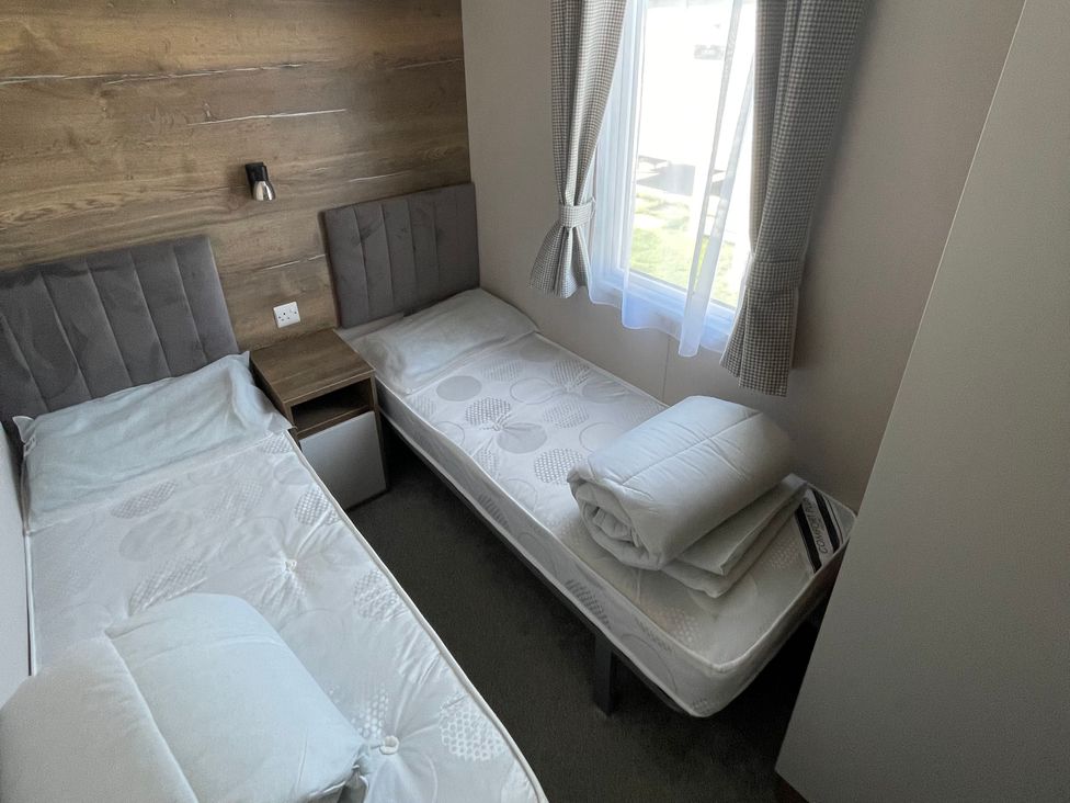 A bedroom with two beds and a nightstand at Unity Beach Burnham-on-Sea