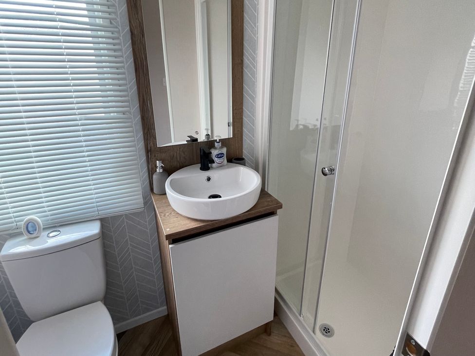 A bathroom with a sink, toilet, shower, and mirror at Unity Beach Burnham-on-Sea