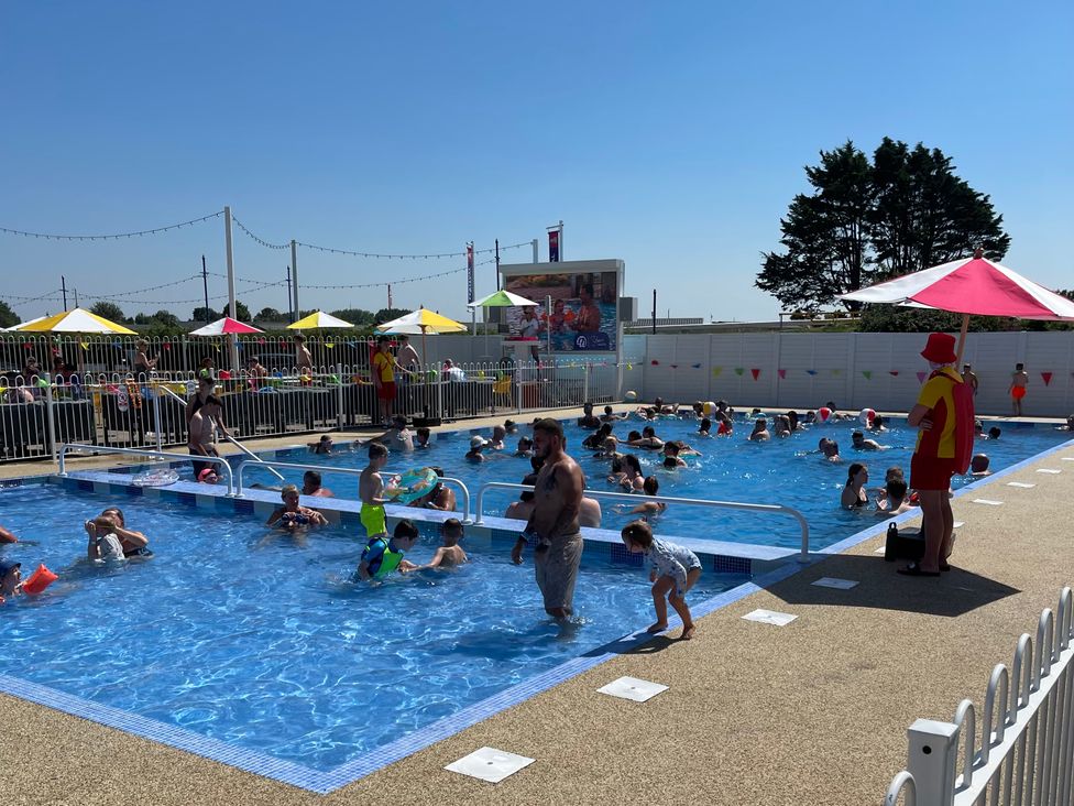 An outdoor pool area with children swimming and lifeguard at Unity Beach Burnham-on-Sea