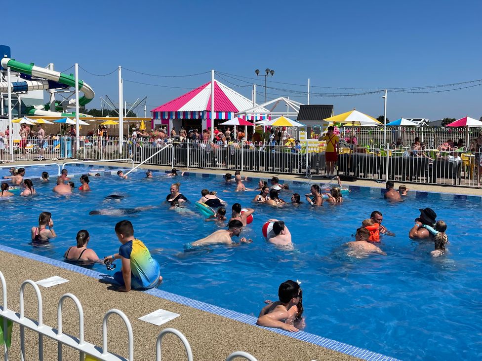 An outdoor pool area with people swimming and a water slide at Unity Beach in Burnham-on-Sea