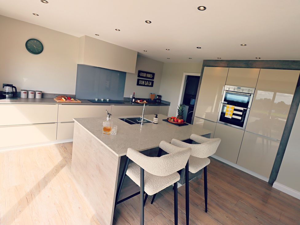 A kitchen with bar stools and a fruit bowl at Parrott's Nest in Hyde