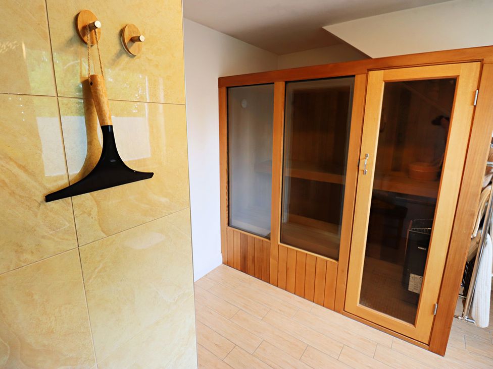 A sauna with glass doors and wooden flooring at Parrott's Nest in Hyde