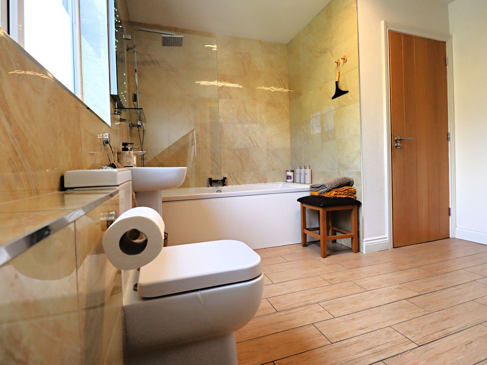 A bathroom with a toilet, bath, sink and towels at Parrott's Nest in Hyde