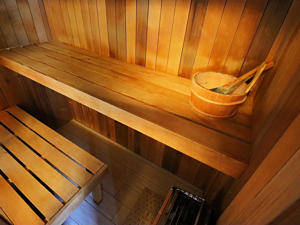 A sauna with wooden benches and a bucket at Parrott's Nest in Hyde