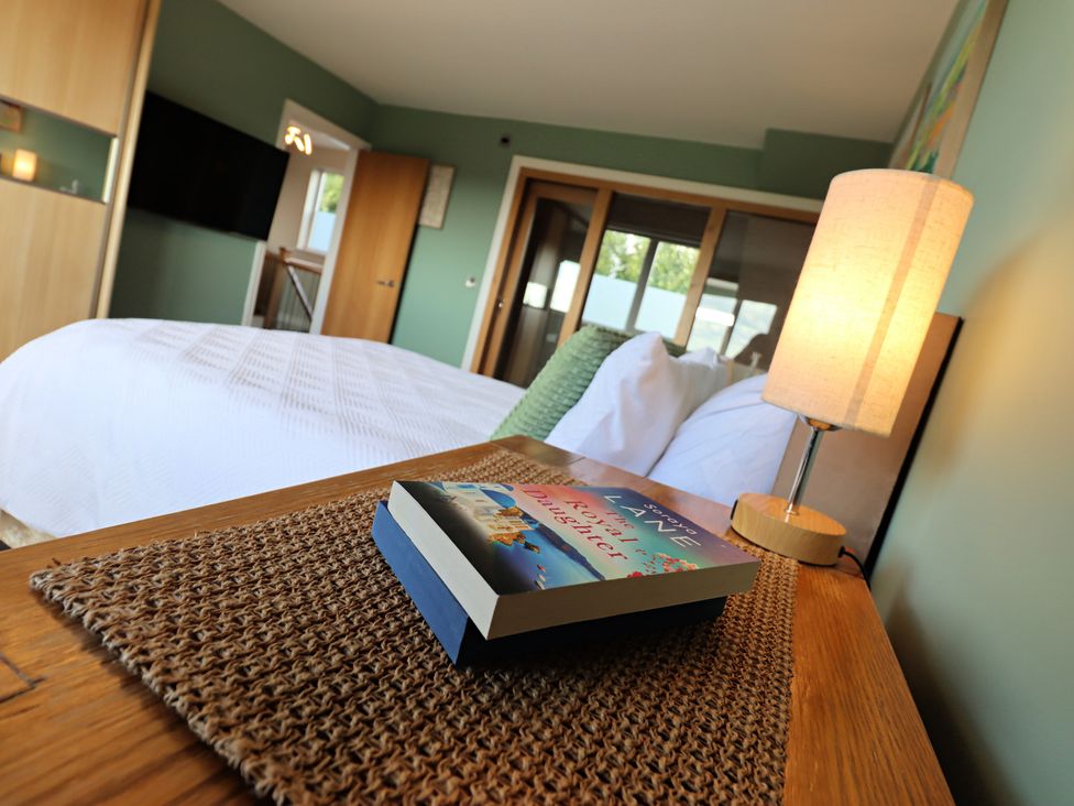 A bedroom with a bed and a book on a nightstand at Parrott's Nest in Hyde