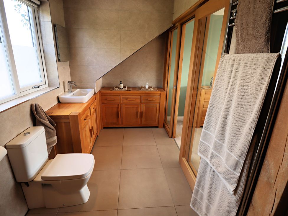 A bathroom with a sink, toilet, and wooden vanity at Parrott's Nest in Hyde