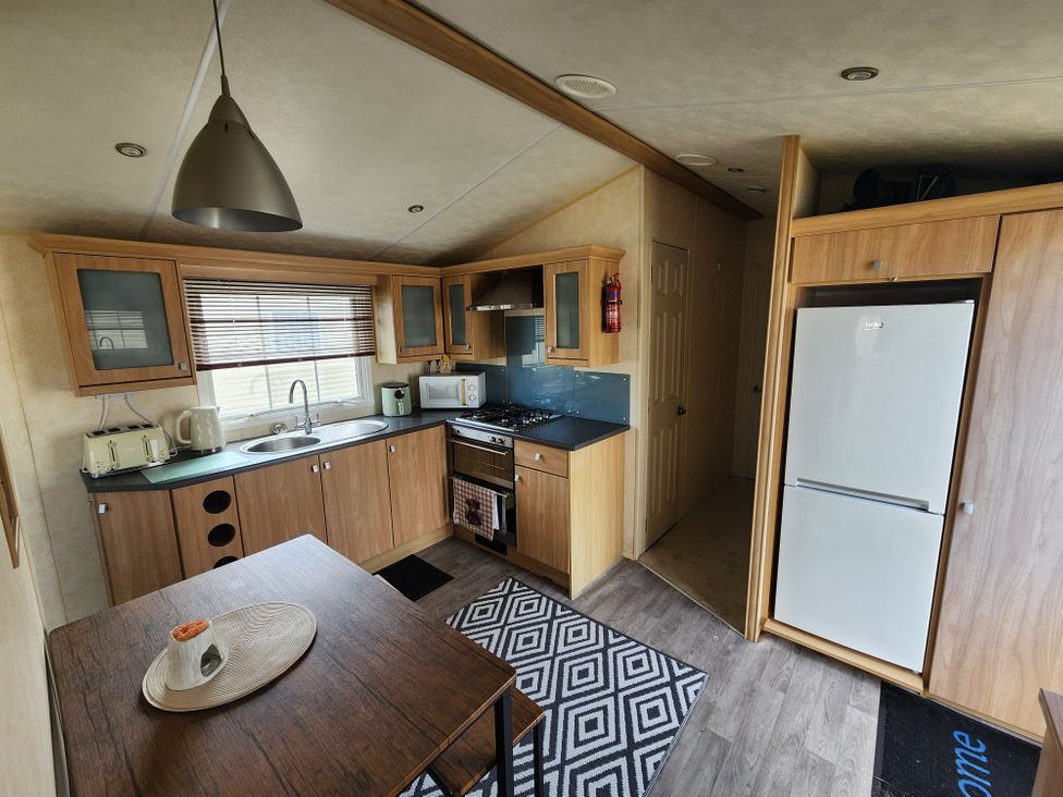 A kitchen with cabinets, appliances, and a dining table at Whitley bay parkdean resorts - 52 Beechfield, Whitley Bay