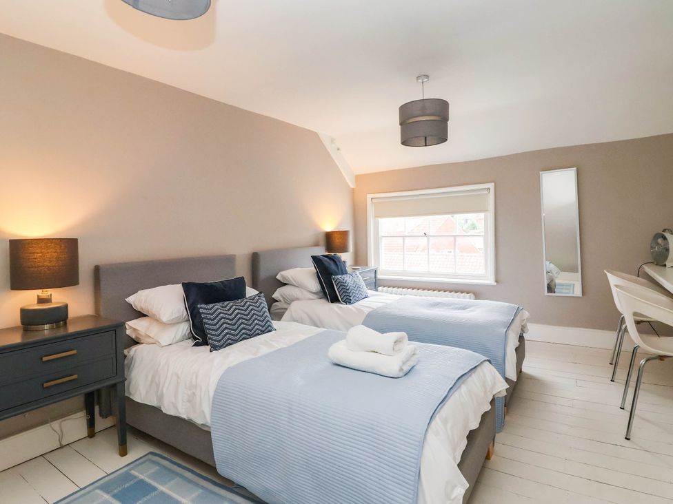 A bedroom with two beds and a table at Cadogan House Easingwold
