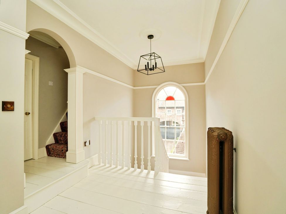 A hallway with a staircase and window at Cadogan House Easingwold