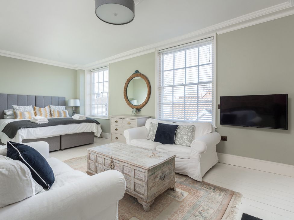 A bedroom with a bed, sofa, coffee table, and TV at Cadogan House in Easingwold