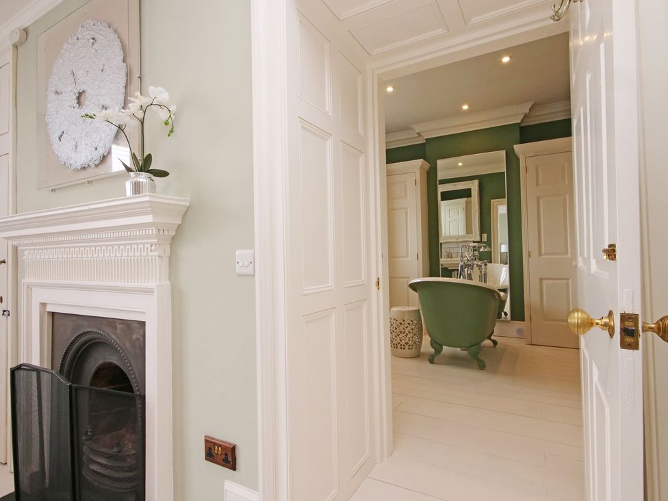 A bathroom with a bathtub and a mirror at Cadogan House Easingwold