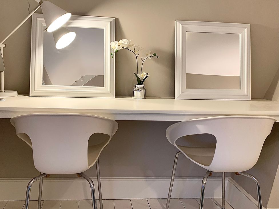 An office setup with a desk, lamps, chairs, and mirrors at Cadogan House in Easingwold