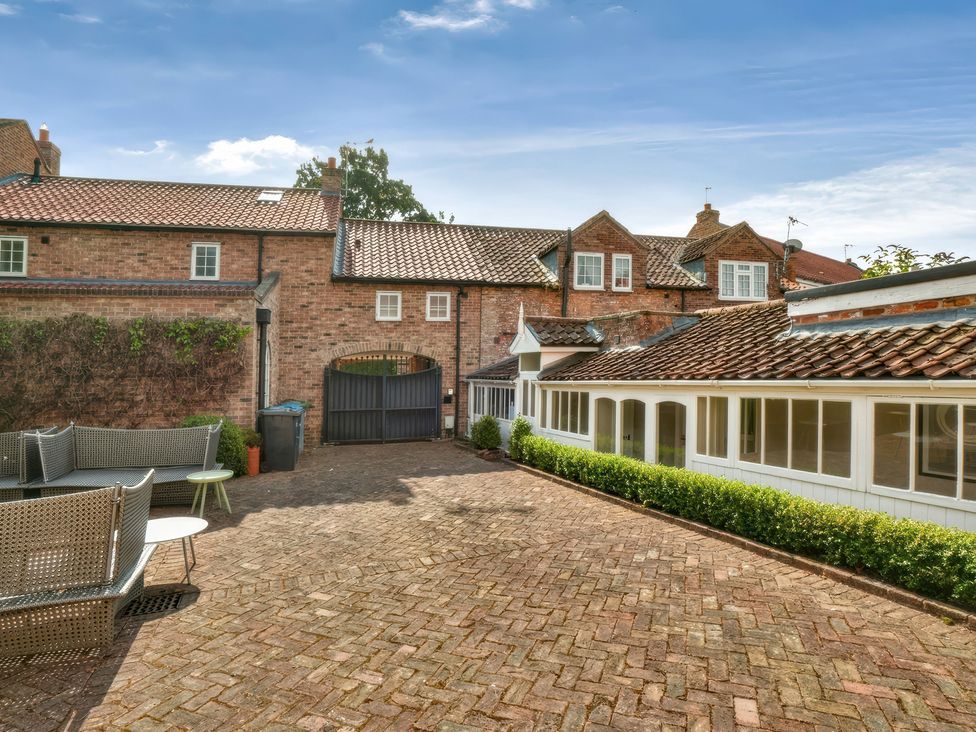 A paved courtyard with seating and buildings at Cadogan House Easingwold