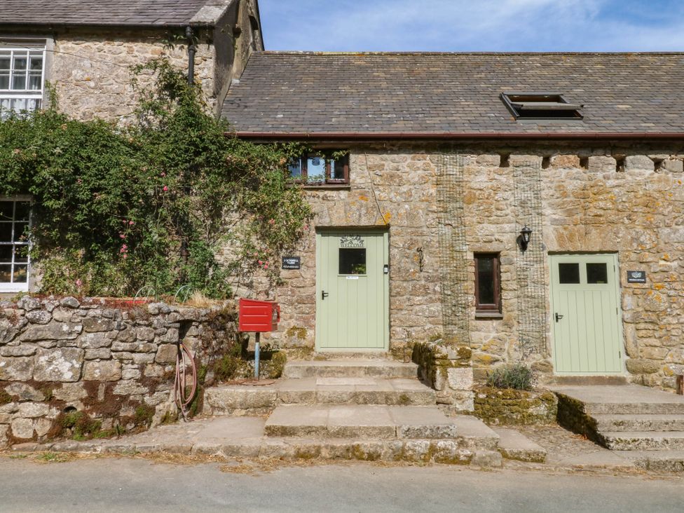 An outdoor view of a stone building with green doors and a red mailbox at Dashel Cottage at Dockwell Farm near Widecombe-In-The-Moor