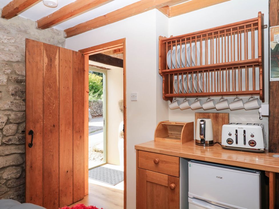 A kitchen with a door and shelves displaying plates and mugs at Dashel Cottage at Dockwell Farm near Widecombe-In-The-Moor