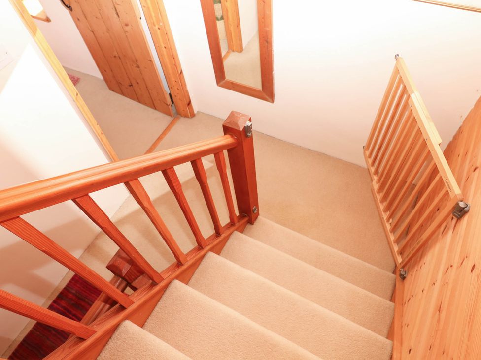 A staircase with a safety gate and mirror in a hallway at Dashel Cottage at Dockwell Farm near Widecombe-In-The-Moor