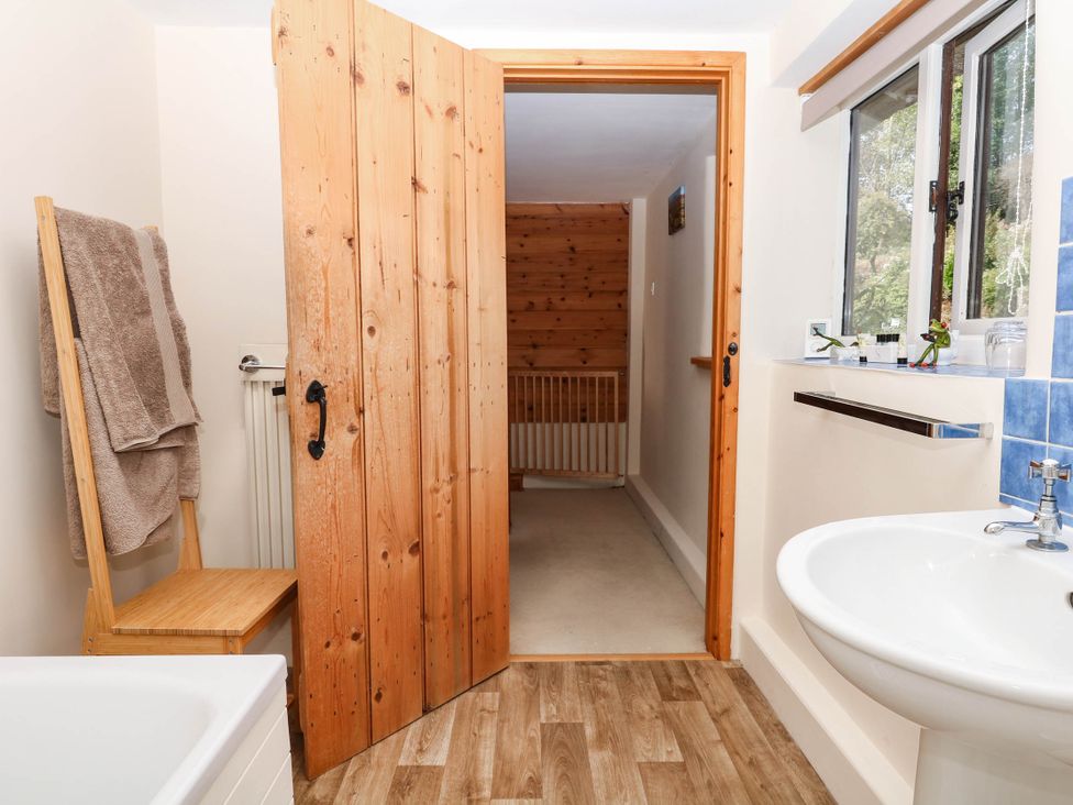 A bathroom with a bath, sink, and towels at Dashel Cottage at Dockwell Farm near Widecombe-In-The-Moor