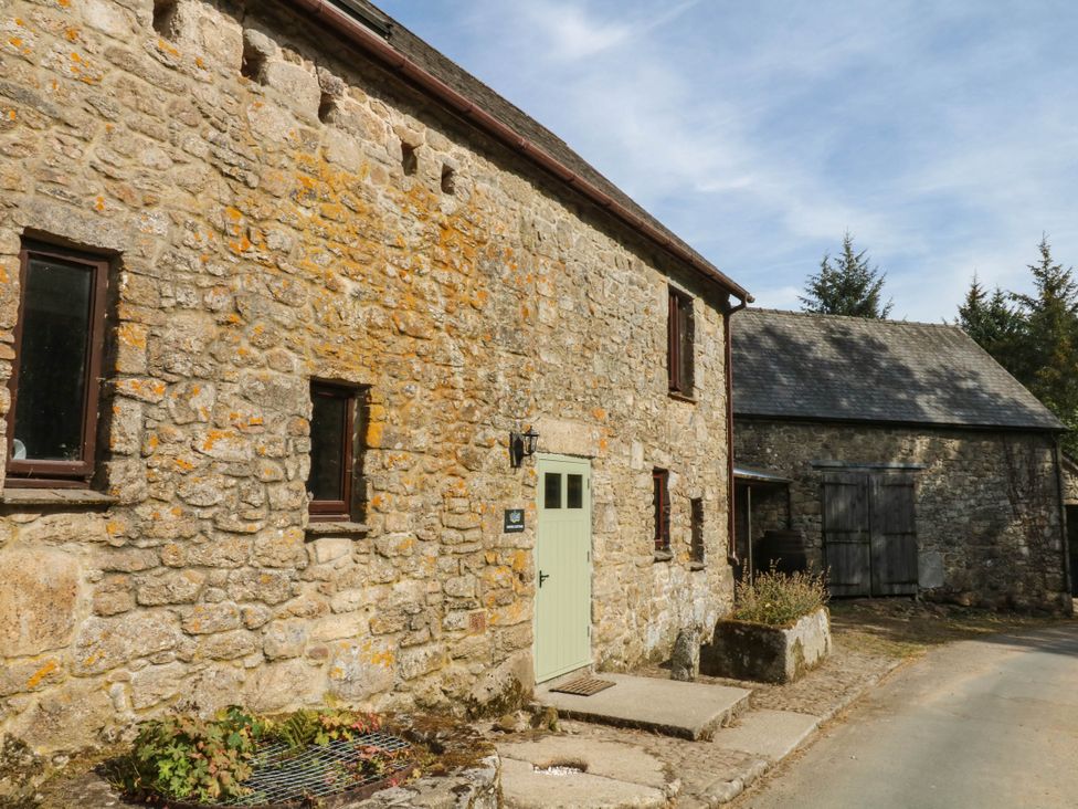 A stone building with windows and a green door at Dashel Cottage at Dockwell Farm near Widecombe-In-The-Moor