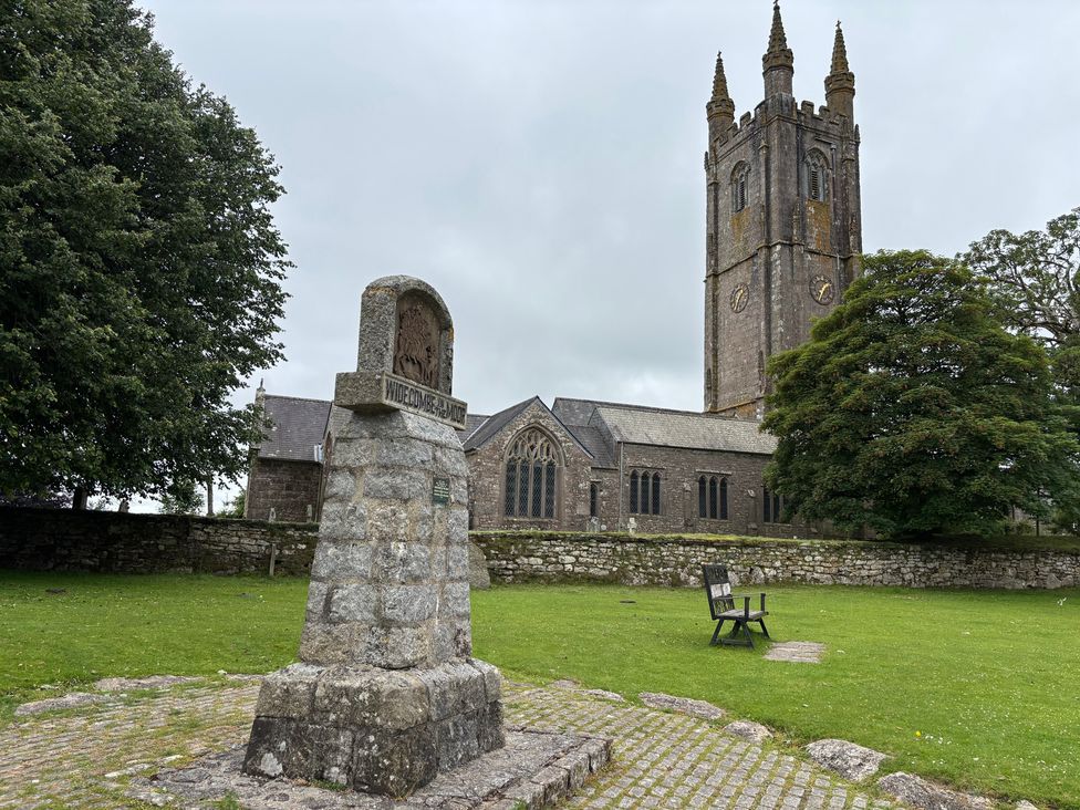 A church tower and stone monument in a grassy area at Dashel Cottage at Dockwell Farm Widecombe-In-The-Moor