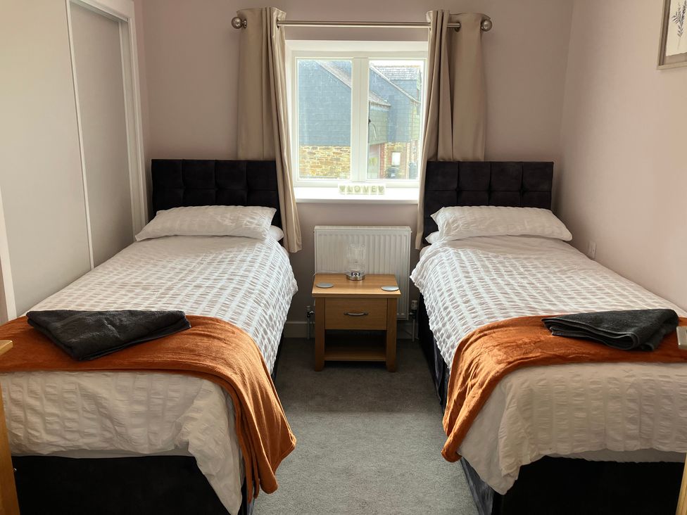 A bedroom with two beds and a table at The Old Dairy near Liskeard
