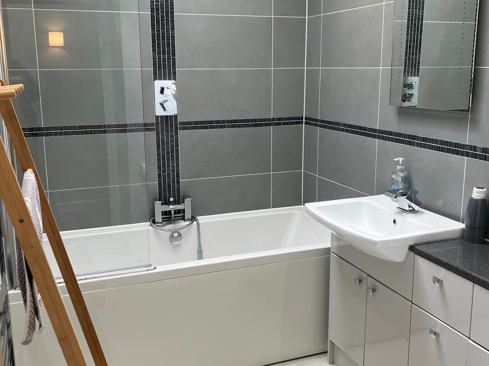 A bathroom with a bathtub, sink and mirror at The Old Dairy near Liskeard
