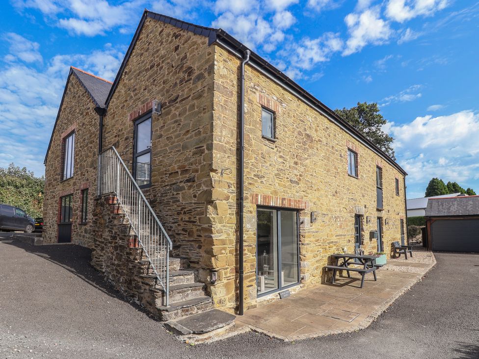 An outdoor view of a stone building with stairs and patio at The Old Dairy near Liskeard