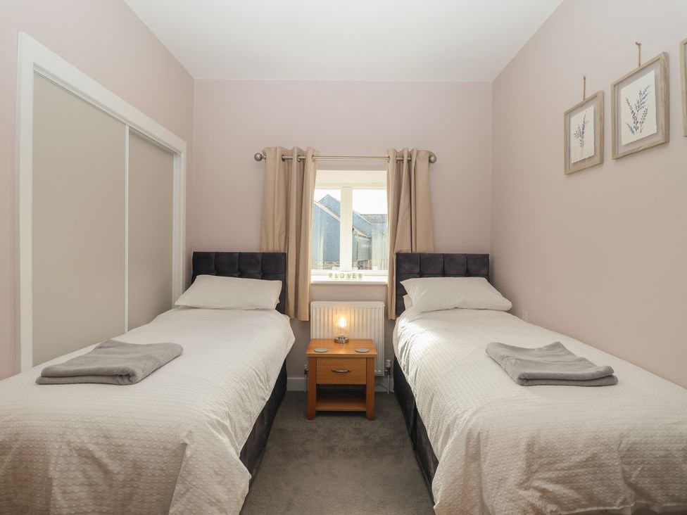 A bedroom with two single beds and a window at The Old Dairy near Liskeard
