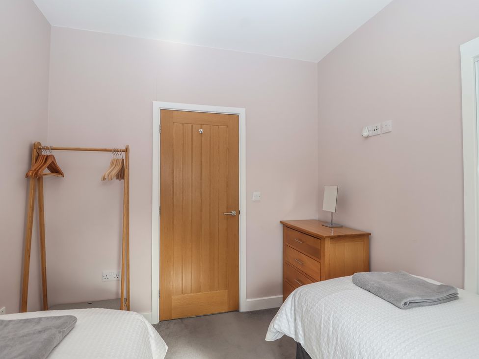 A bedroom with two beds and a wooden door at The Old Dairy near Liskeard