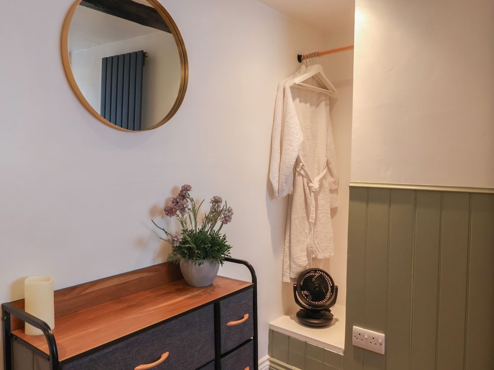 A hallway with a mirror, robe, plant and drawer unit at Cathedral Mews in Ripon