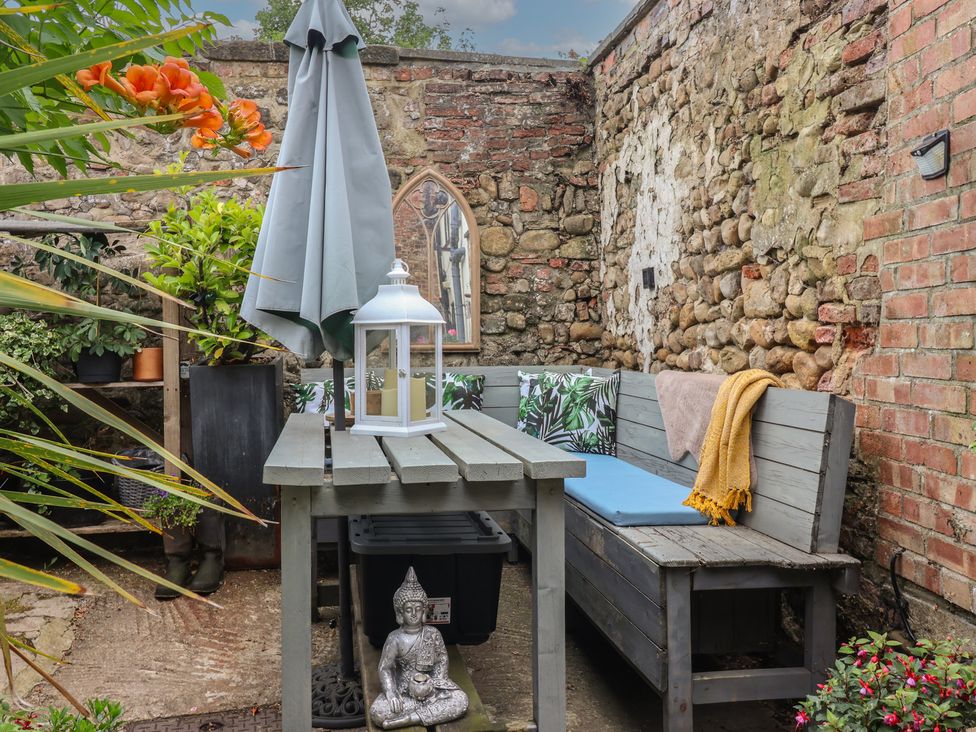 A garden with a table, bench, and plants at Cathedral Mews, Ripon