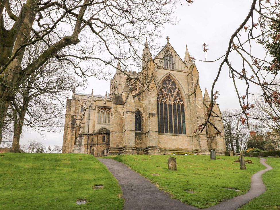 A church with a large window and surrounding trees and path in Ripon