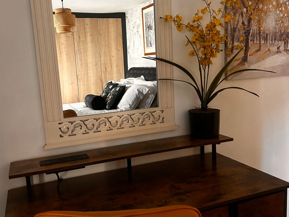 A desk with a mirror and flowers at Old Cottages: 3 Bed in Ripon
