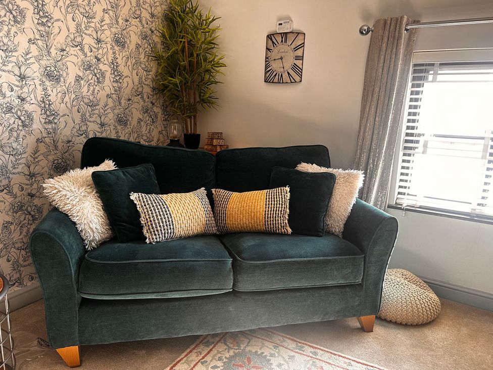 A sofa with cushions and a plant in a living room at Old Cottages: 3 Bed in Ripon