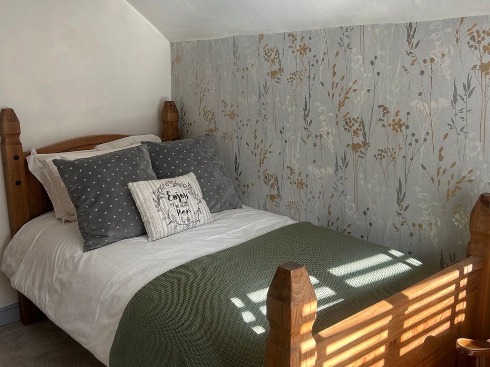 A bedroom with a bed and floral wallpaper at Old Cottages: 3 Bed in Ripon