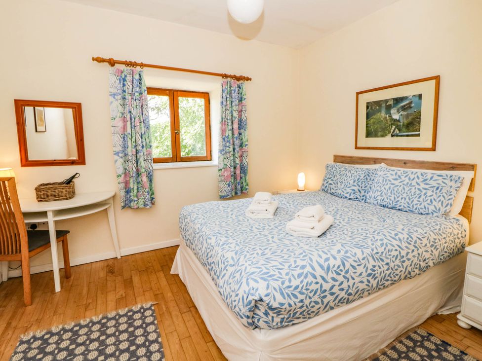 A bedroom with a double bed and a desk at May Cottage in St Davids