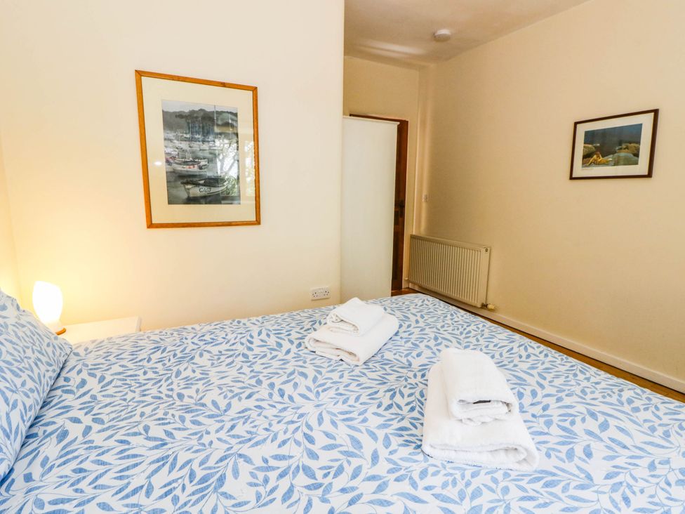 A bedroom with a bed and towels at May Cottage in St Davids