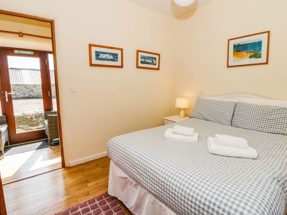 A bedroom with a double bed and a door leading outside at May Cottage in St Davids