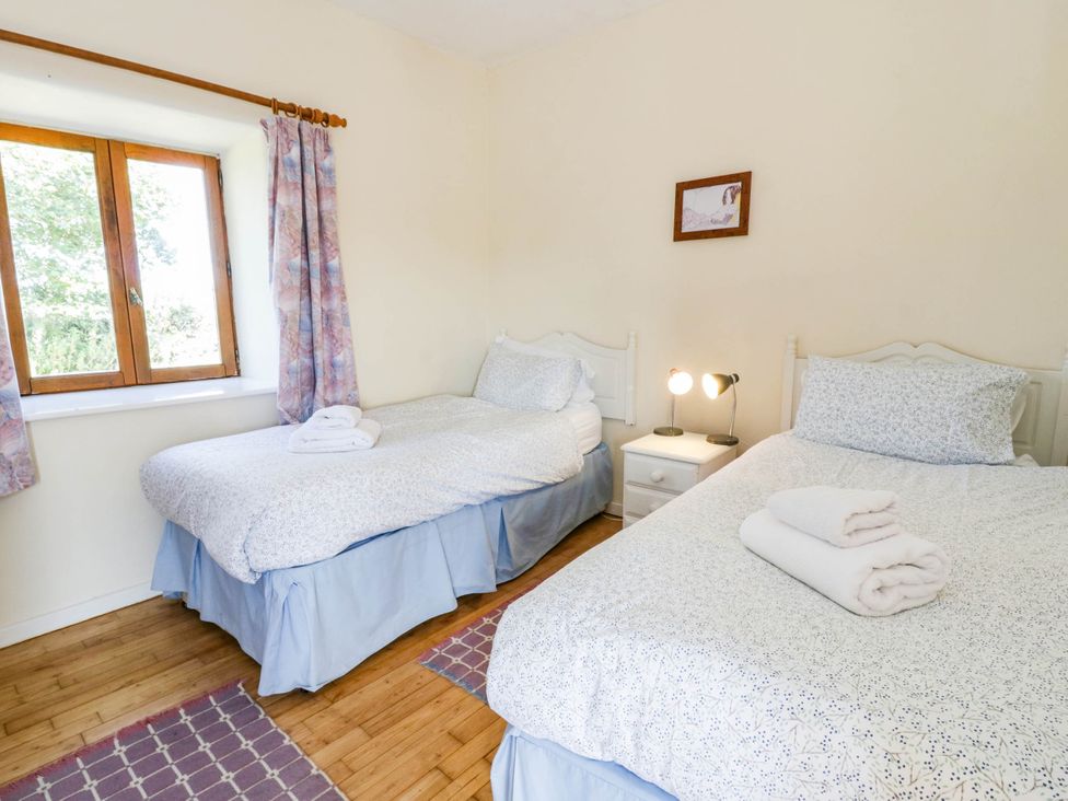 A bedroom with two beds and a window at May Cottage in St Davids
