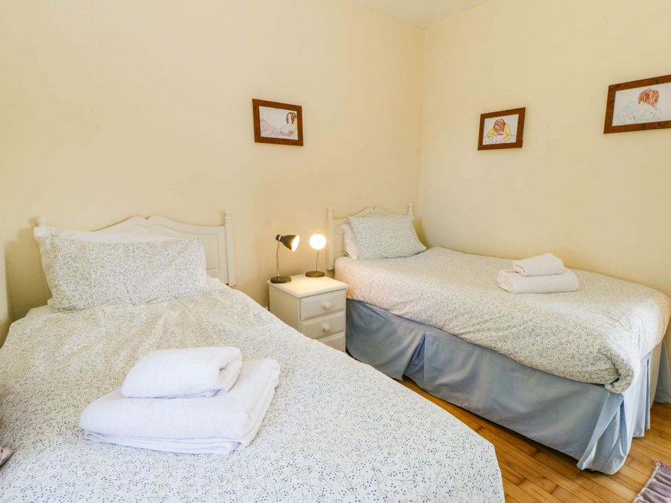 A bedroom with two beds and a bedside lamp at May Cottage St Davids