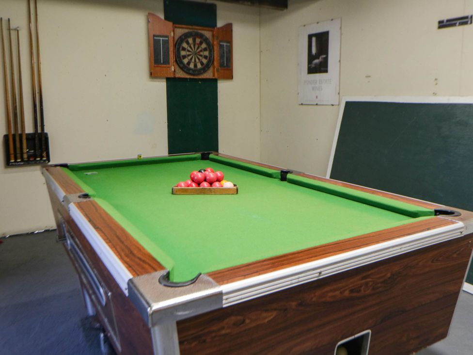 A pool table with balls and a dartboard at May Cottage St Davids