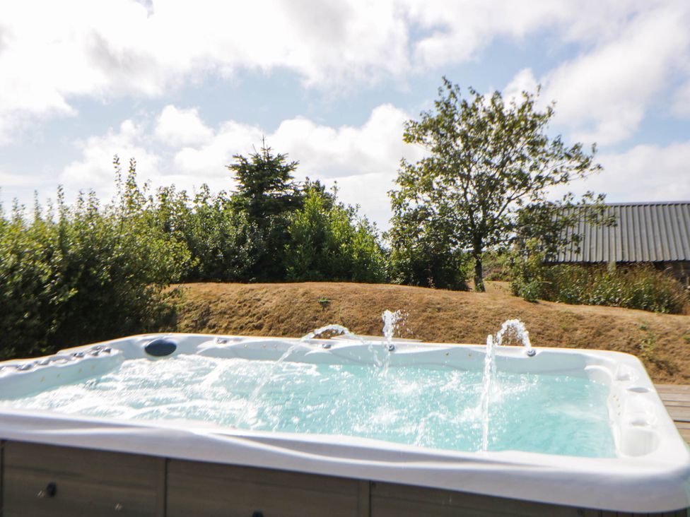 A hot tub with water features and greenery at May Cottage St Davids